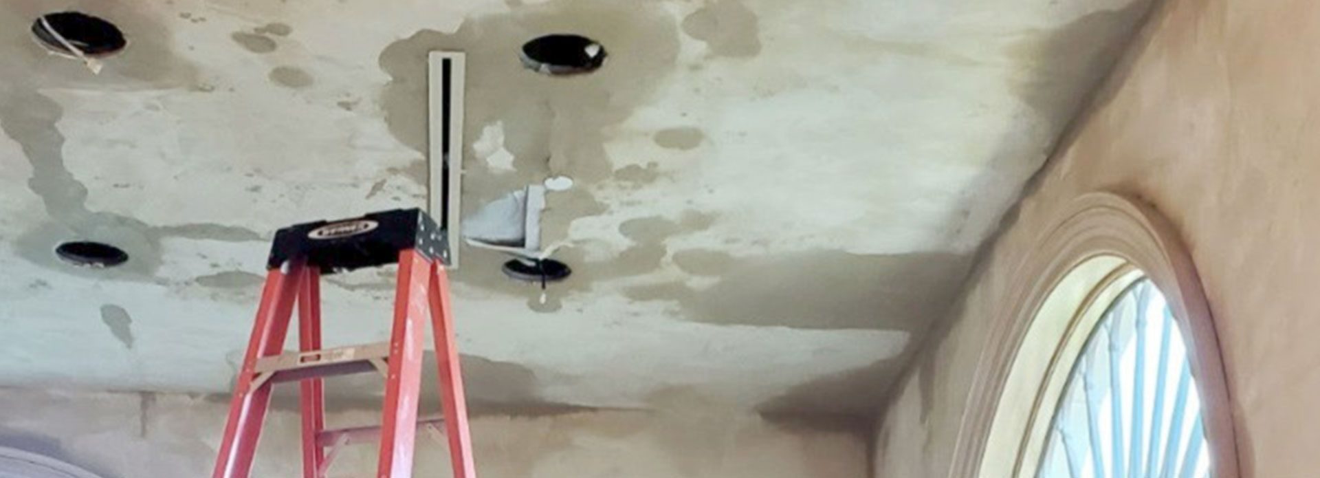 Water-stained ceiling with a ladder set up for inspection and repair