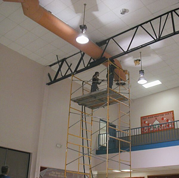 Crew on scaffolding cleaning ceiling ductwork in a gymnasium