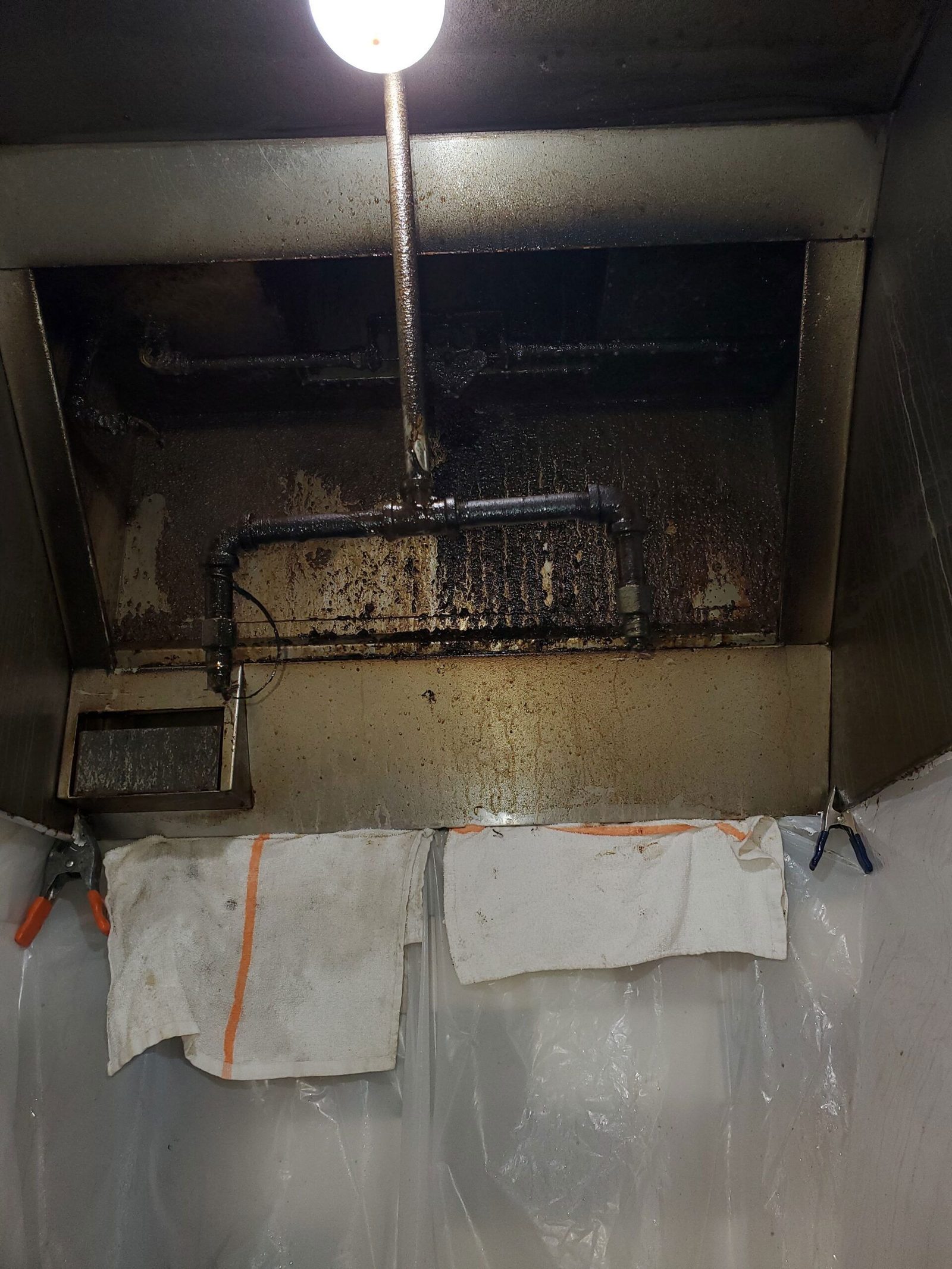 Grease-coated commercial kitchen hood before cleaning