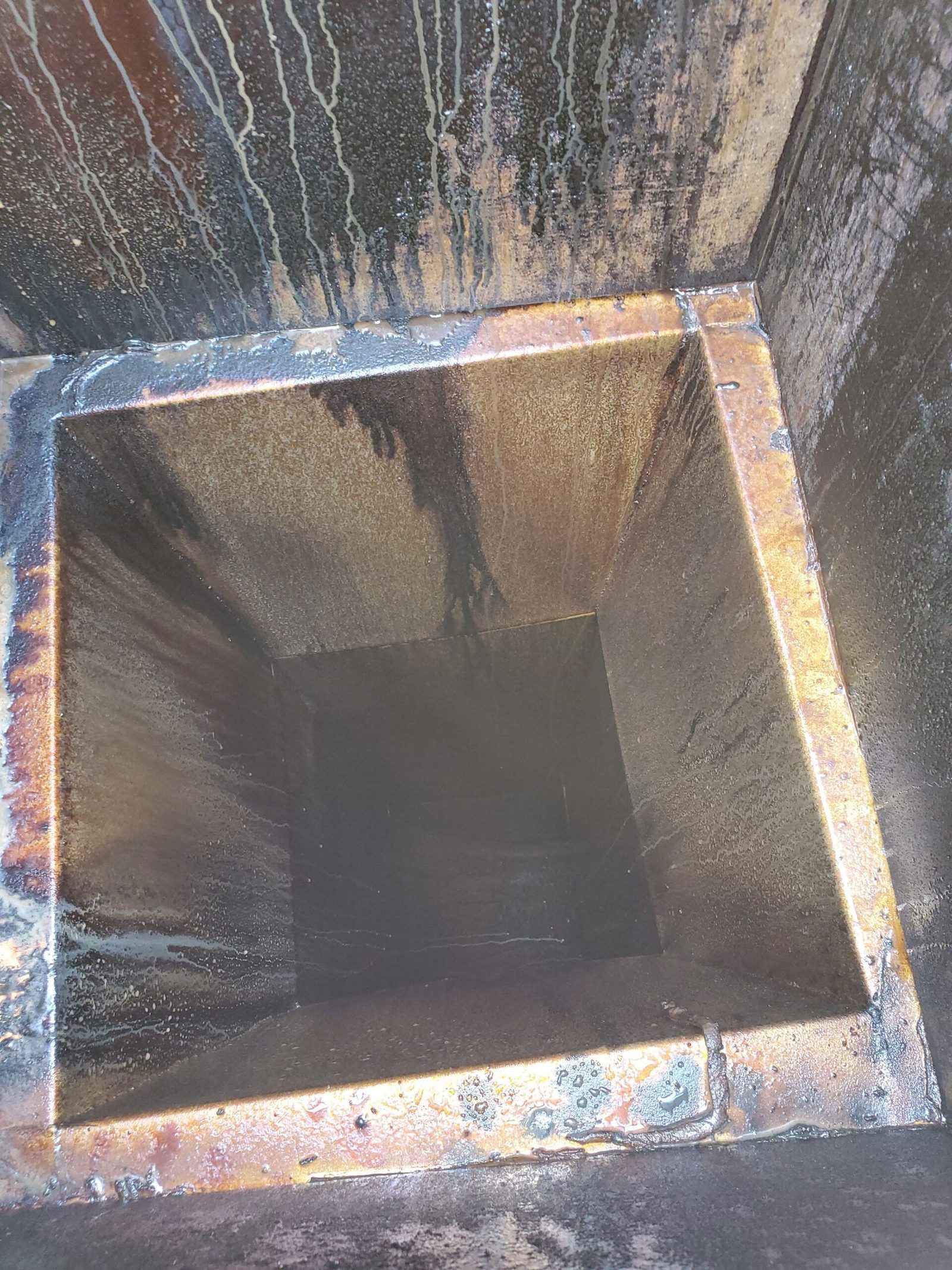 Grease-caked exhaust duct riser before cleaning