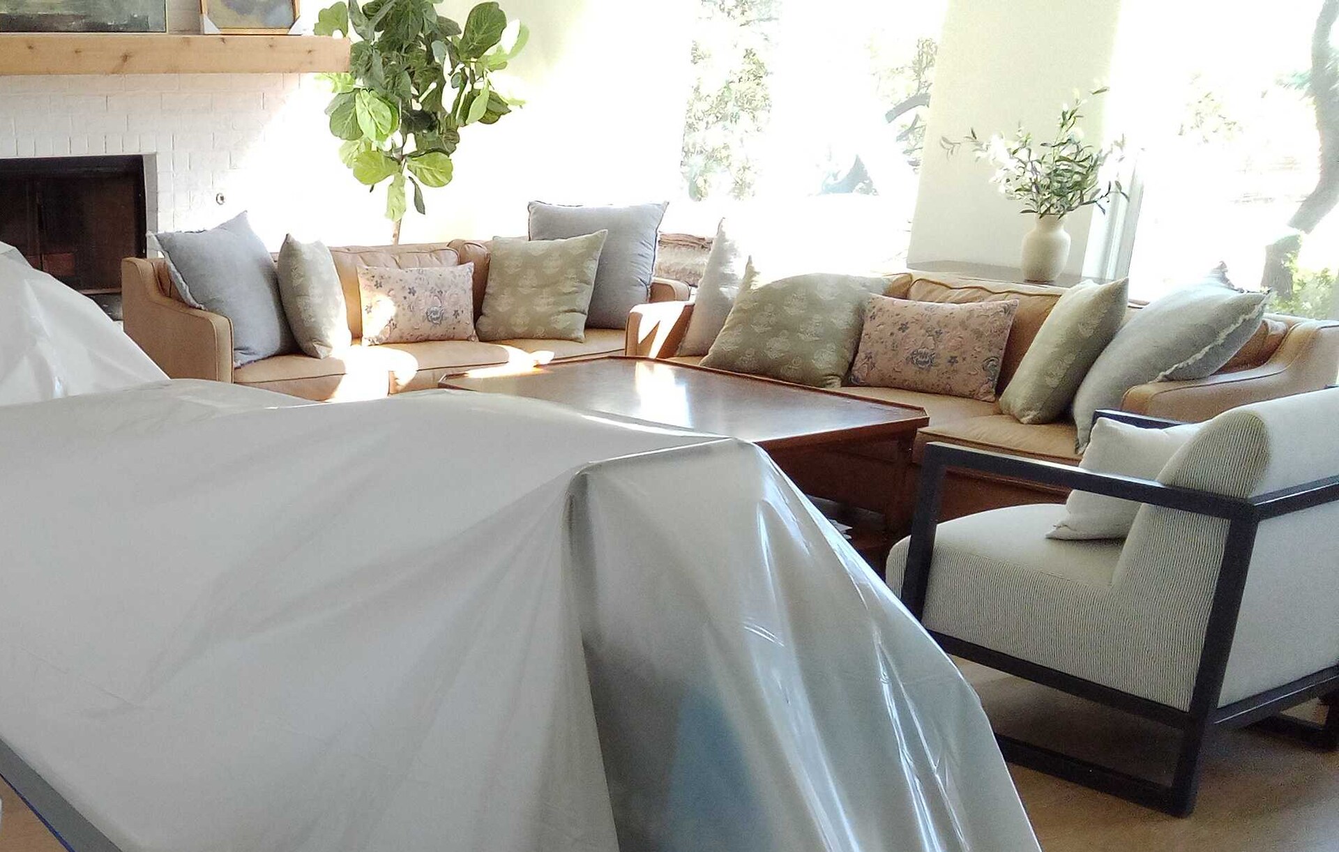 Living room furniture sealed under containment plastic beside a staircase during a residential job
