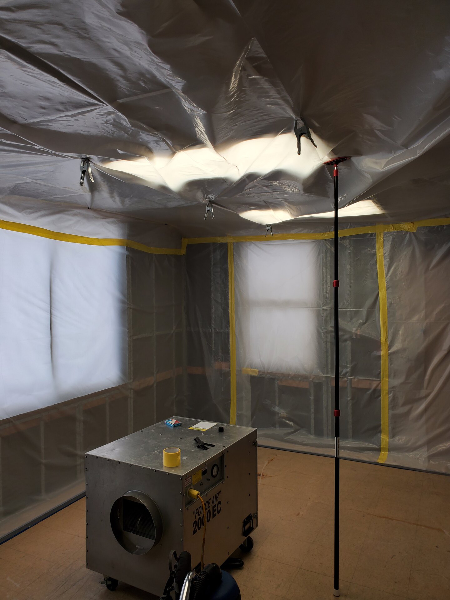 Sealed containment built with telescoping poles and taped plastic, with an air scrubber running inside