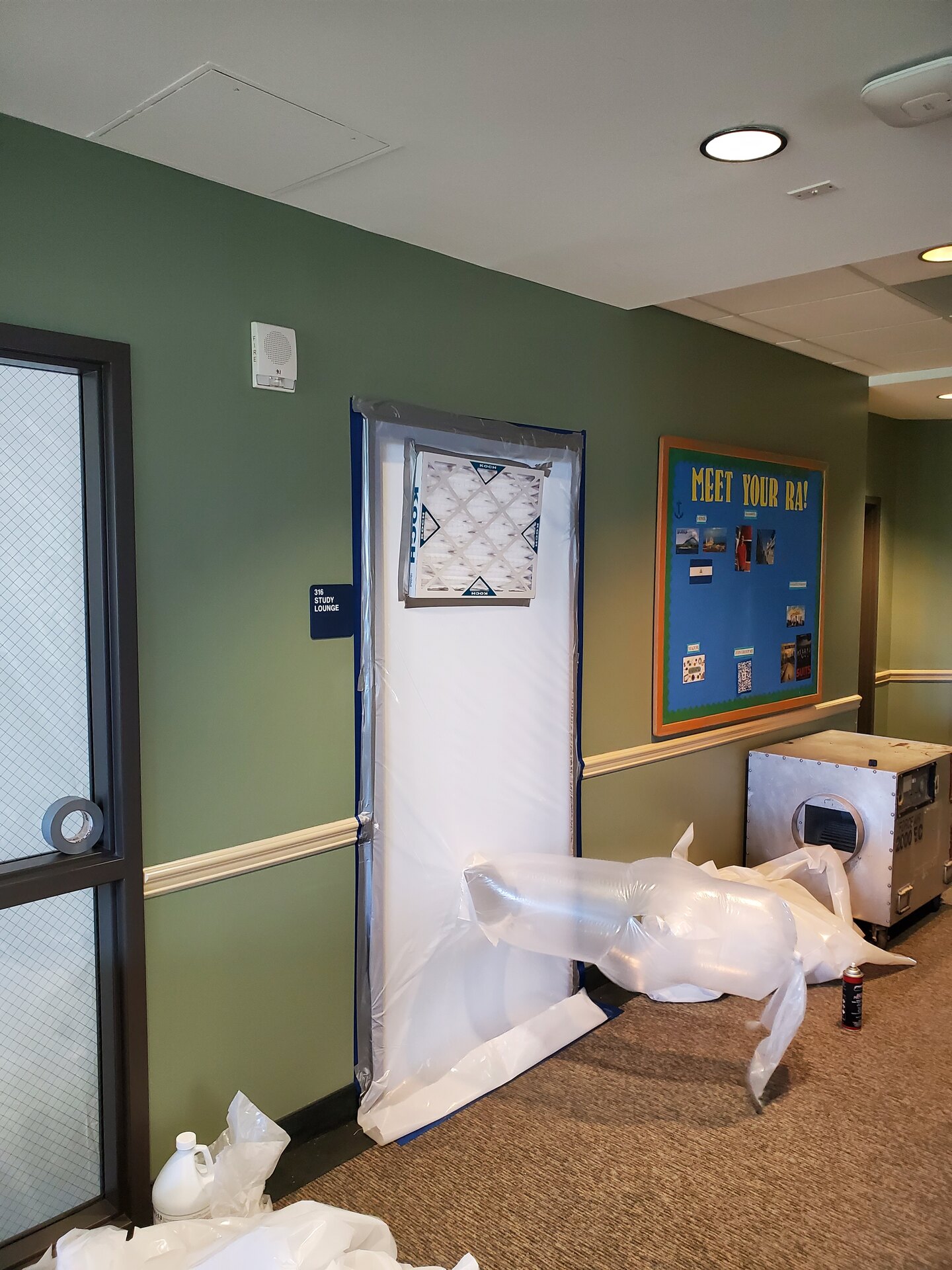 Filtered decontamination entry sealed over a dormitory study lounge door during remediation