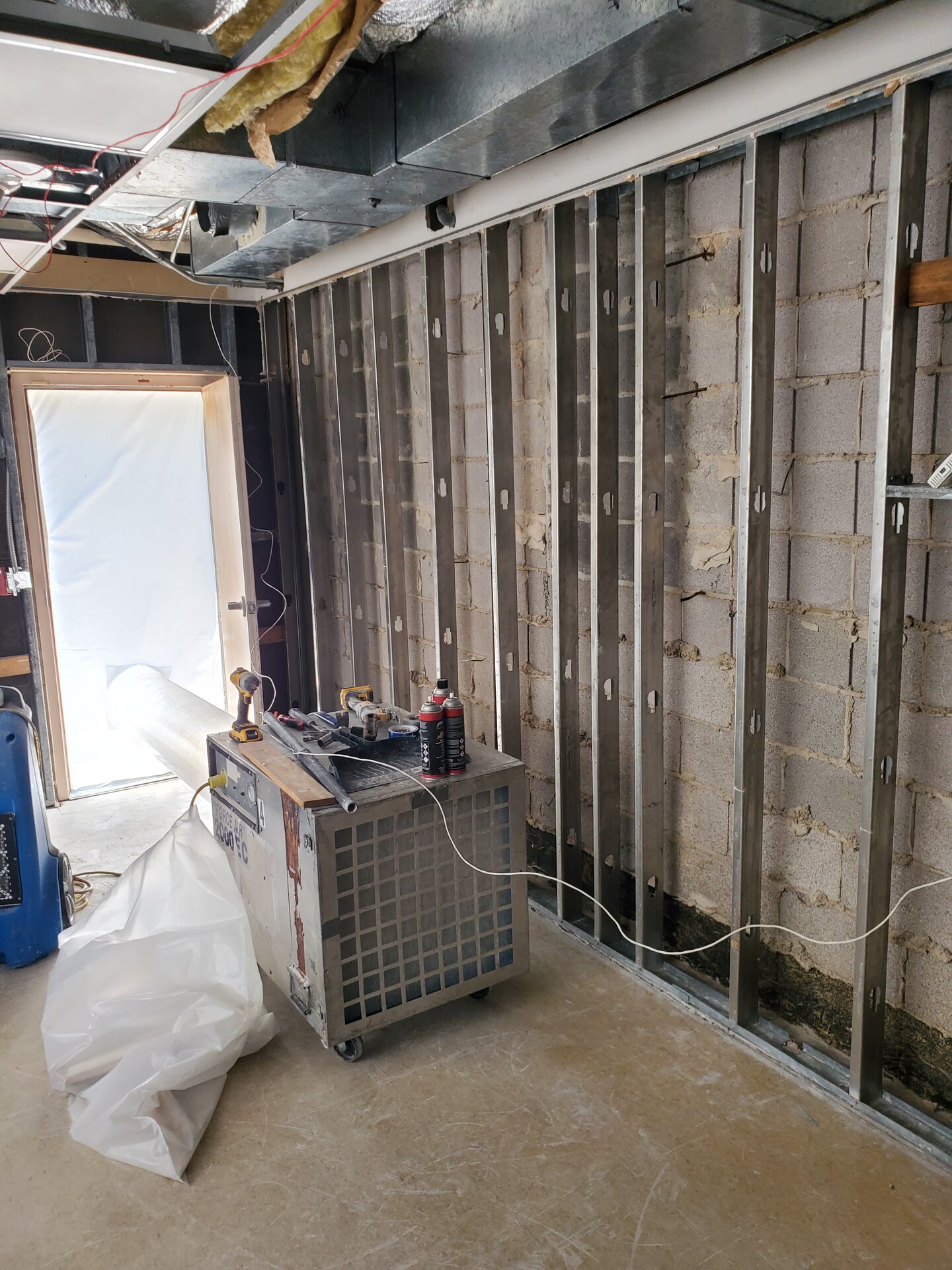 Commercial room stripped to the metal studs after demolition with a dehumidifier running