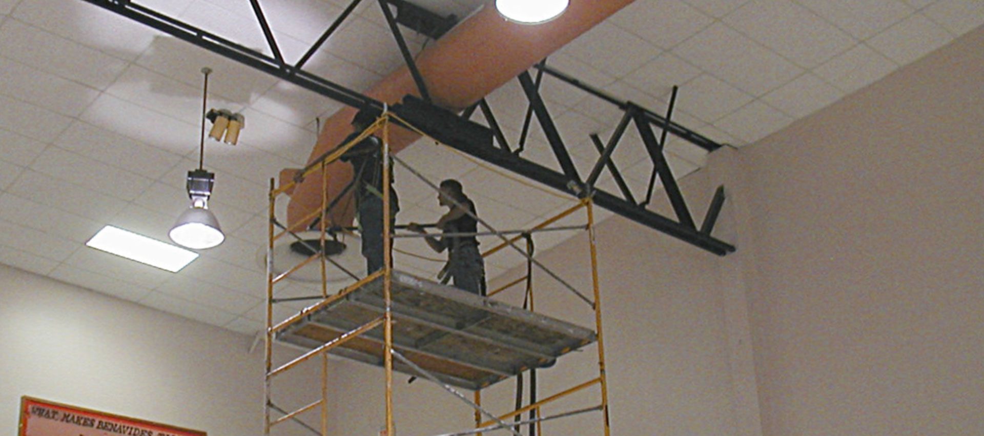Fresh Air crew on scaffolding cleaning overhead ductwork in a school gymnasium