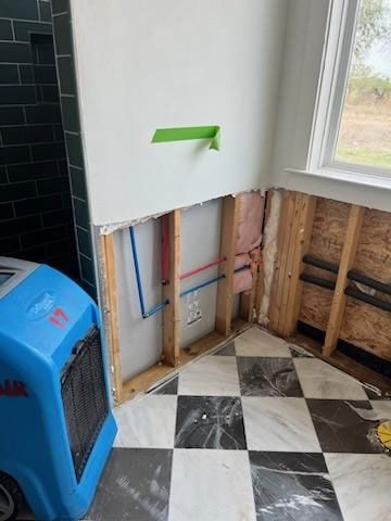Wall opened to the studs with a dehumidifier drying the room