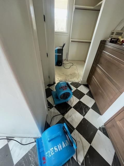 Air mover drying a tiled hallway after water intrusion